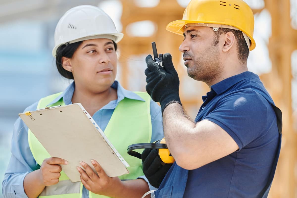 A site engineer and a foreman with a clipboard and radio on a building site
