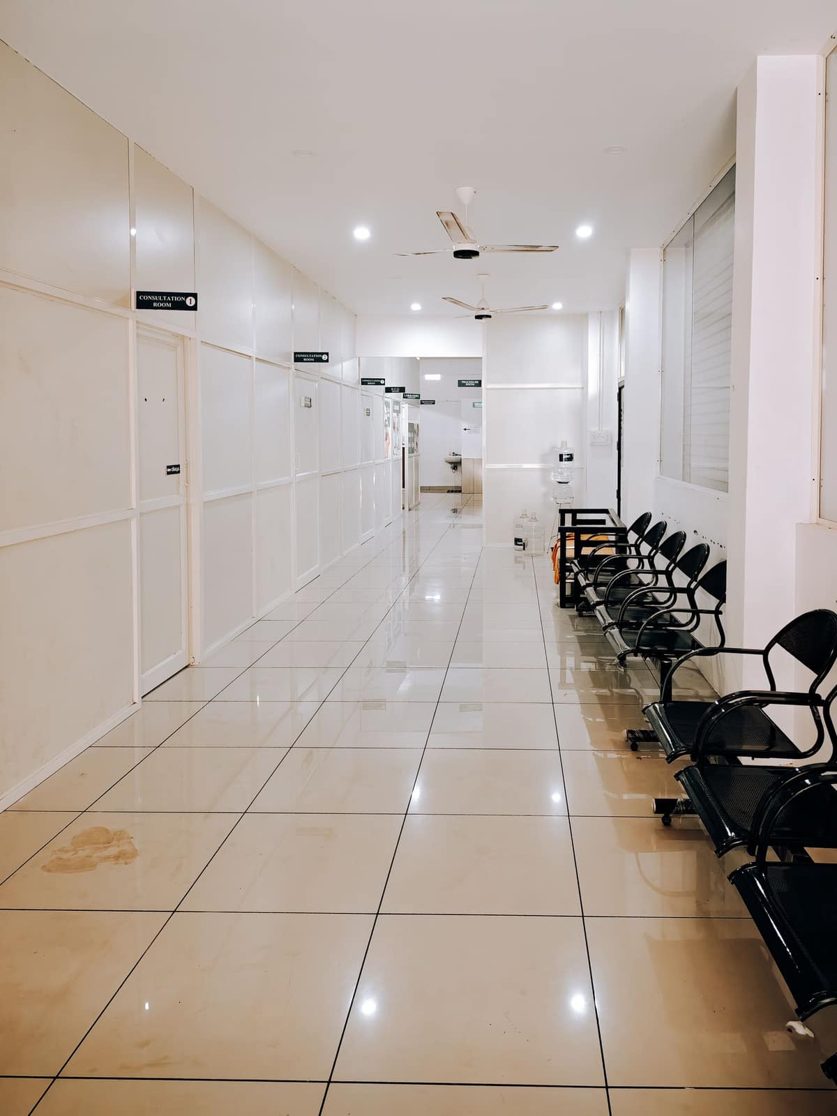A bright empty medical corridor with a row of waiting chairs