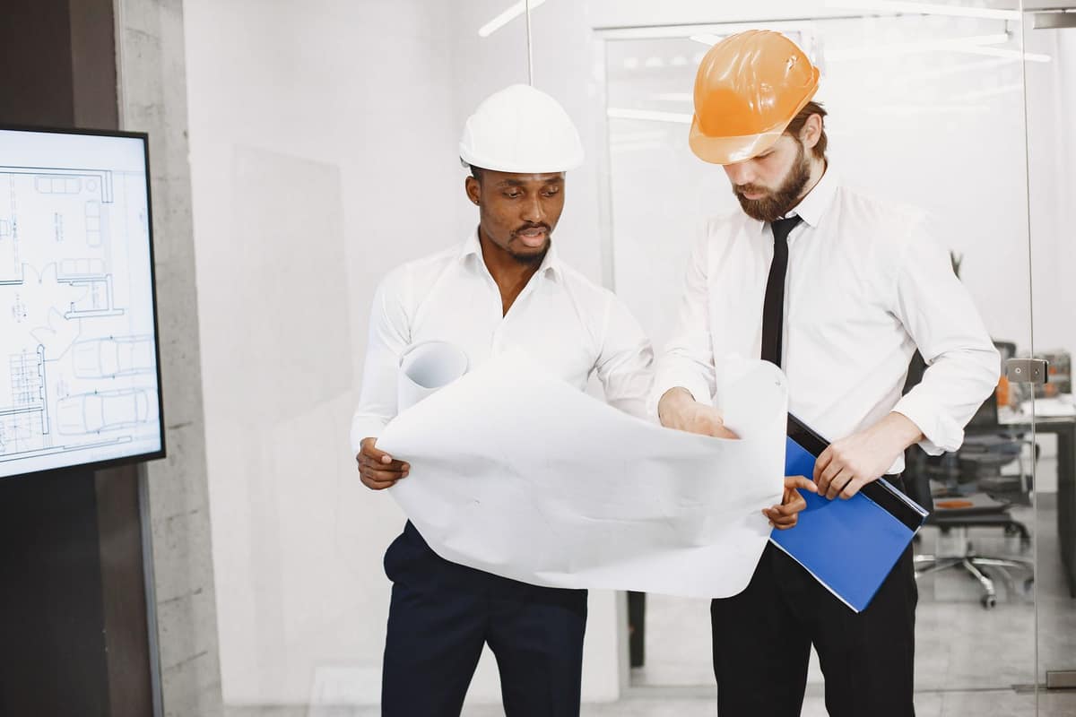 Two people in hard hats reviewing building plans together